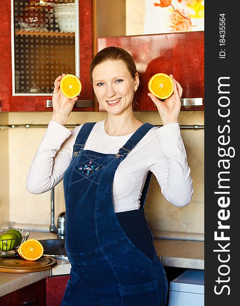 Beautiful pregnant woman at kitchen with orange