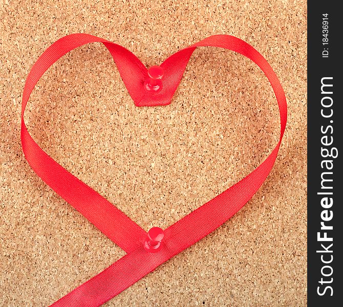 Red heart shaped ribbon pinned to cork board