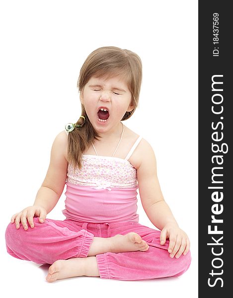 Sleepy little girl sits like a turk on white and yawning