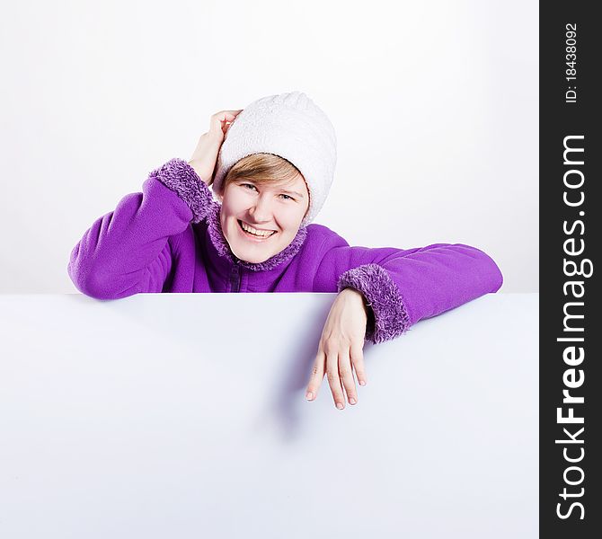 Young woman in a warm cap and a sweater showing empty white board