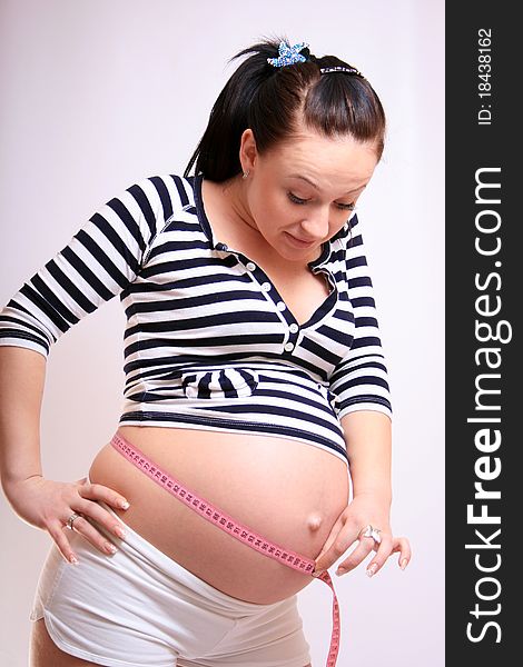Pregnant woman measuring her belly over white