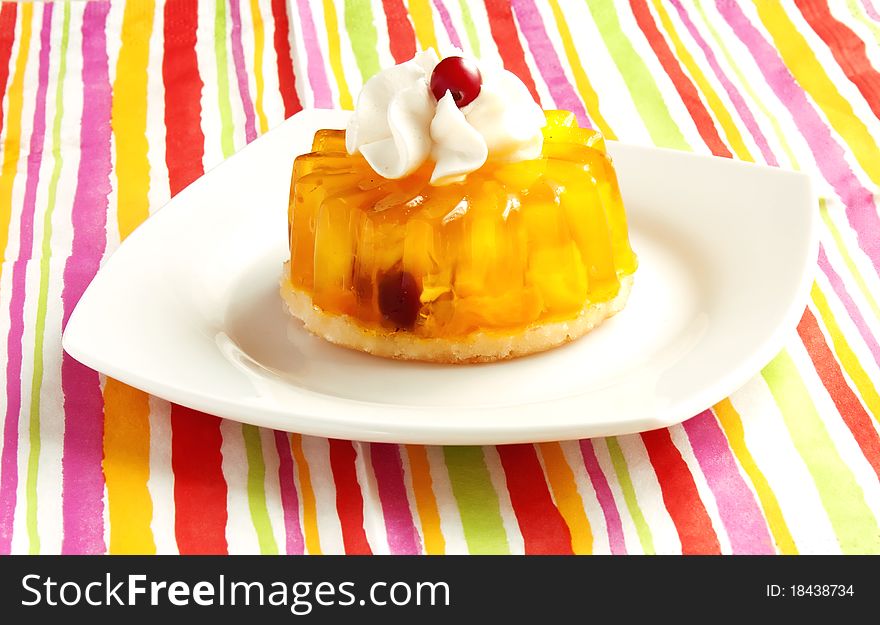 Tart with whipped cream on a white platte on a striped background