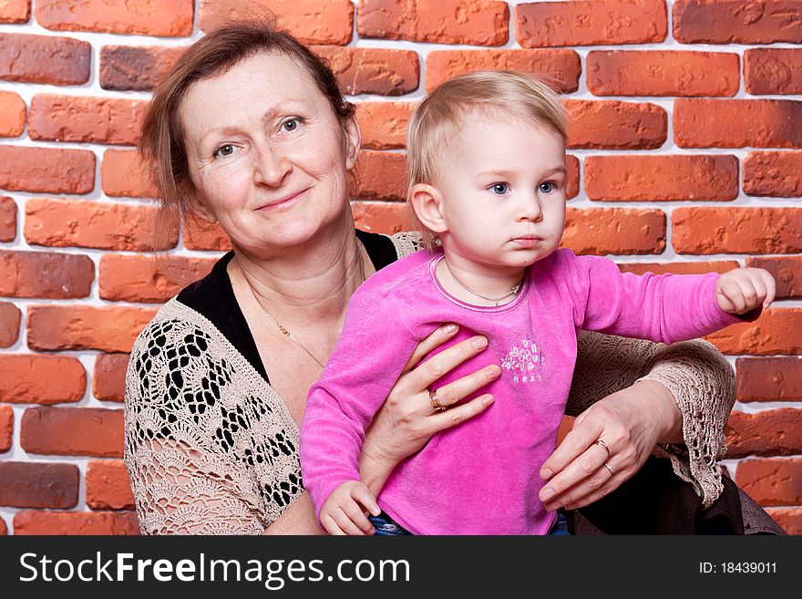 Grandmother kissing her grand daughter against brick wall. Grandmother kissing her grand daughter against brick wall