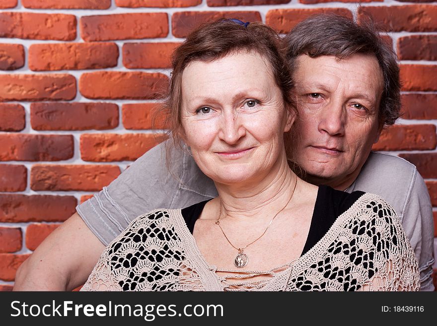 Happy seniors couple in love against brick wall