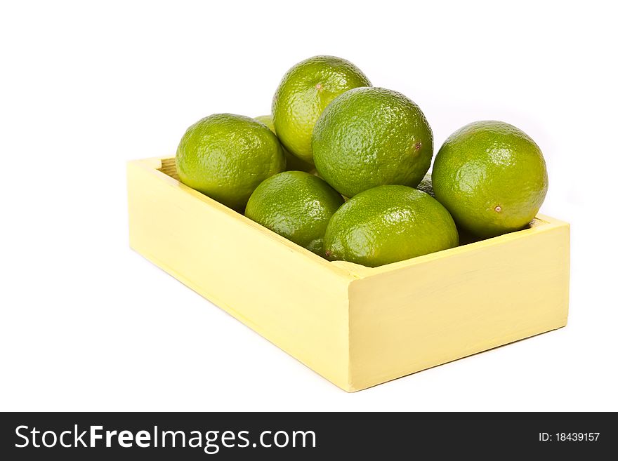 Pile of fresh limes in a wooden box across white. Pile of fresh limes in a wooden box across white