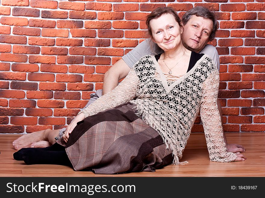 Happy seniors couple in love against brick wall