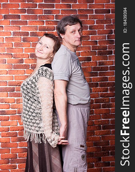 Happy seniors couple in love against brick wall