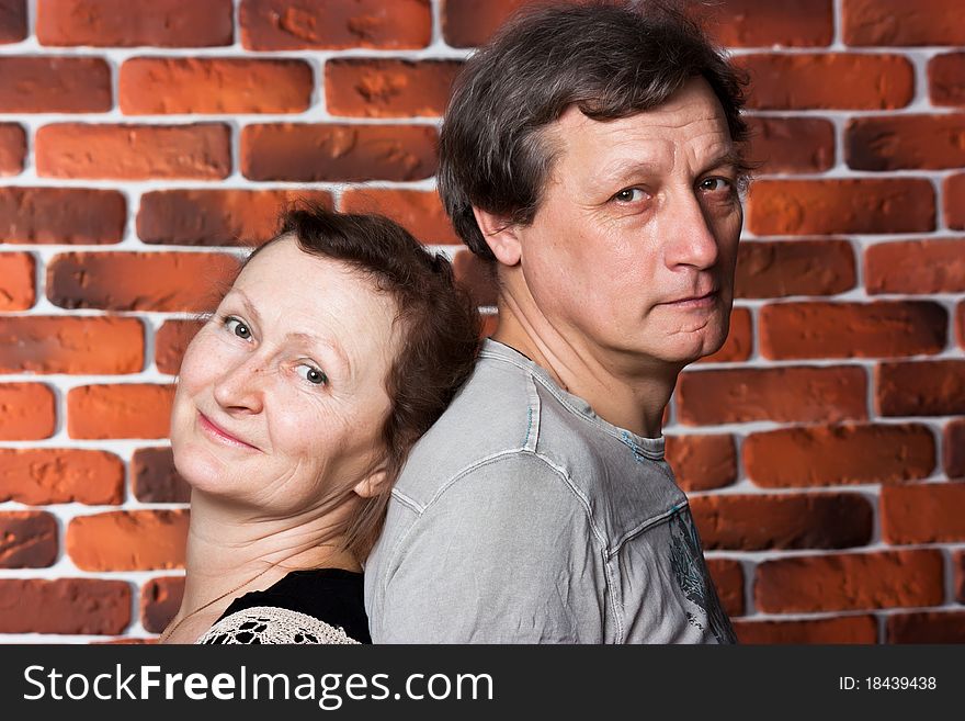 Happy seniors couple in love against brick wall