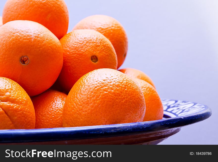 Fresh Oranges in a bowl in front of a blue wall