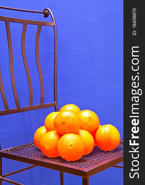 Fresh Oranges on an iron chair in front of a blue painted wall