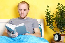 Man Lying In Bed And Reading Book Royalty Free Stock Image