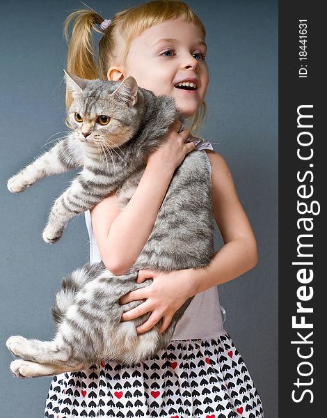 A girl with blond hair is holding a cat and laughs. A girl with blond hair is holding a cat and laughs