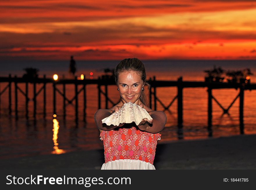 Beautiful young woman holding a seashell during the sunset. Beautiful young woman holding a seashell during the sunset.