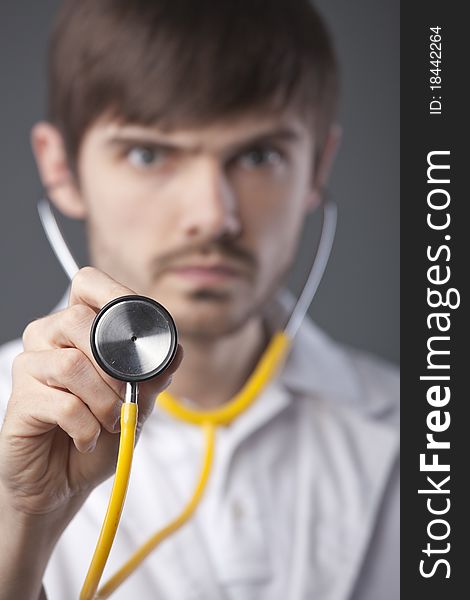 Doctor using stethoscope - focus on hand in foreground