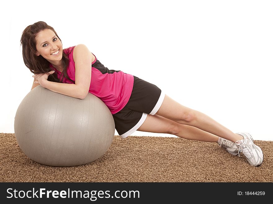 A woman is sideways leaning on a large fitness ball. A woman is sideways leaning on a large fitness ball.