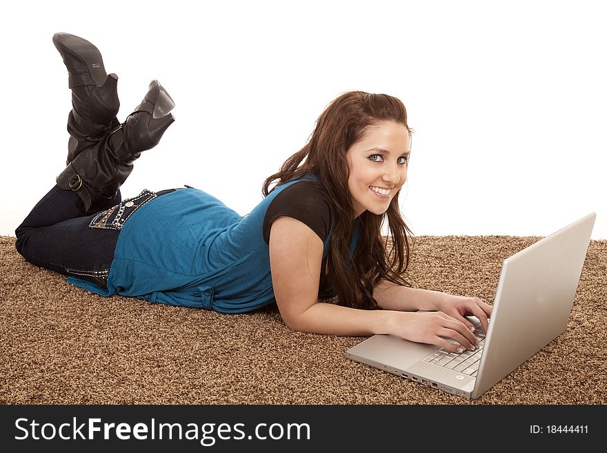A woman with a laptop computer is laying on the floor smiling. A woman with a laptop computer is laying on the floor smiling.