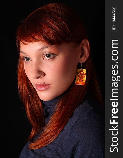 The red-haired girl looking through a shoulder on a black background. The red-haired girl looking through a shoulder on a black background