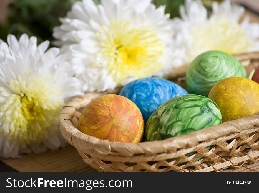Easter colored eggs in a wicker vase of chrysanthemums. Easter colored eggs in a wicker vase of chrysanthemums