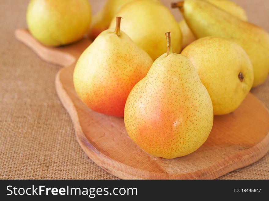 Bunch of fresh yellow pears on wooden board and mesh background