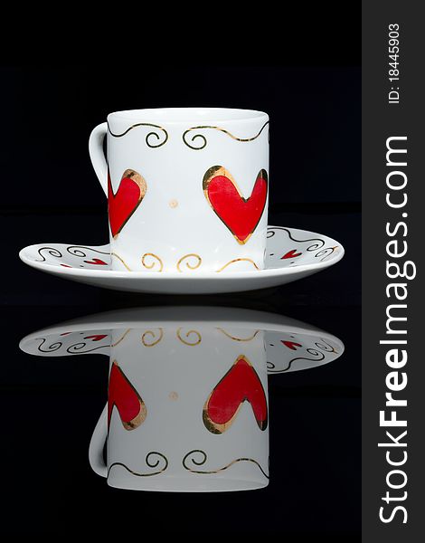 White cup with hearts is a black table, reflected in it. White cup with hearts is a black table, reflected in it.