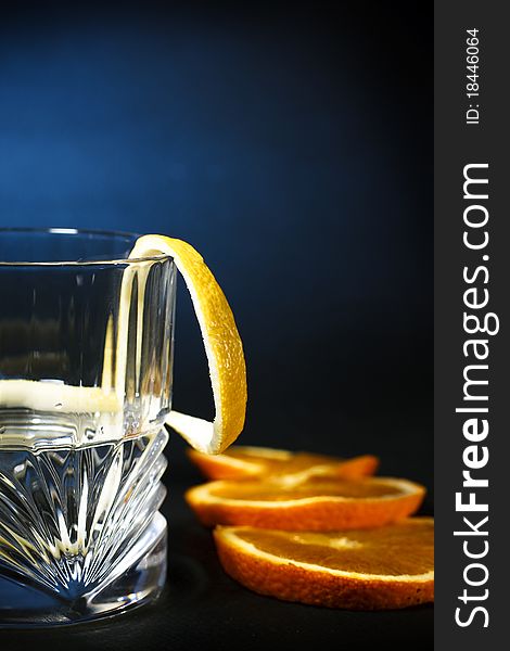 Cold vodka in a glass, with decor oranges and lemon, closeup. Cold vodka in a glass, with decor oranges and lemon, closeup