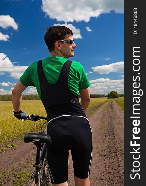 Young man against blue sky with a cycle