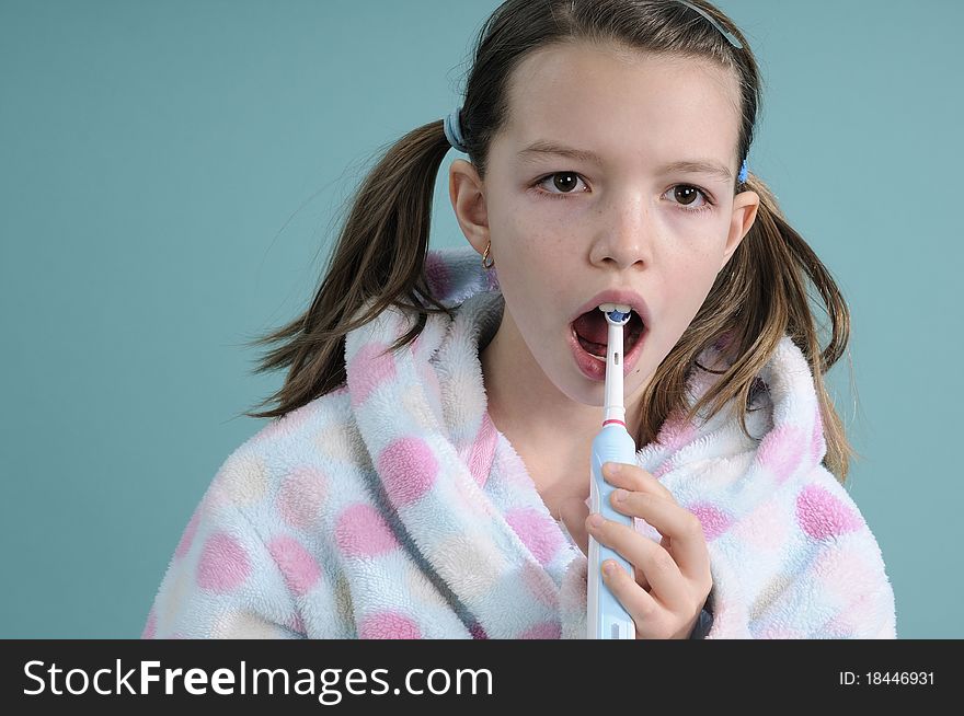 White girl dressed in bathrobe studying electric toothbrush movements. White girl dressed in bathrobe studying electric toothbrush movements