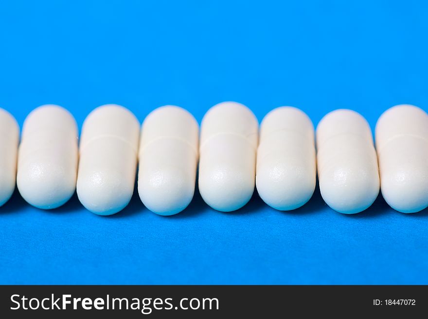 Macro view of white pills on a blue background