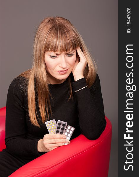 Woman With Headache And Pills Sitting On Sofa