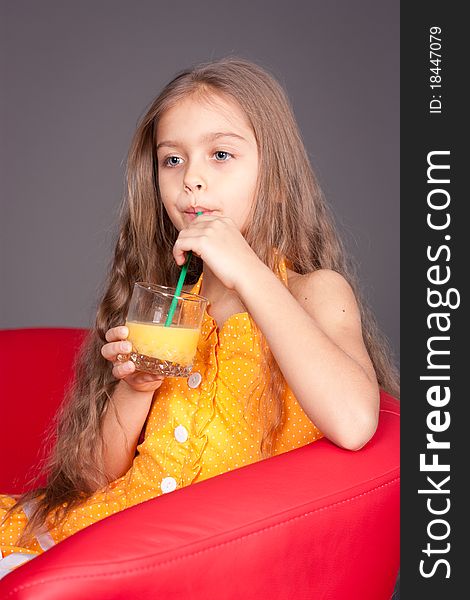 Beautiful young girl drinking orange juice in the studio