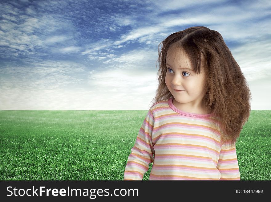 The smiling child against the blue sky and a green field