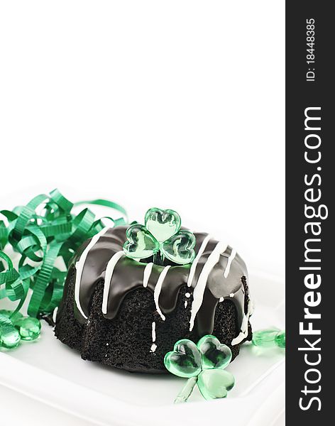 A small Saint Patrick's Day chocolate bundt cake with green ribbons and shamrock decorations, vertical with white copy space. A small Saint Patrick's Day chocolate bundt cake with green ribbons and shamrock decorations, vertical with white copy space