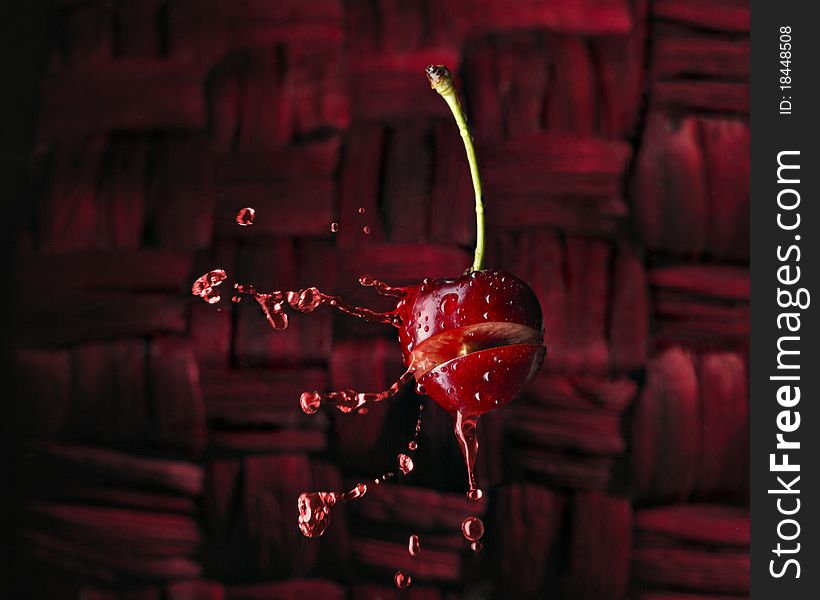 Red chery with liquid splash of juice on red background