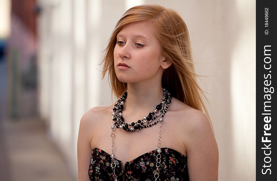 A picture of a lovely blond teenage girl in a lovely tube top and necklaces, standing on sidewalk in a city. A picture of a lovely blond teenage girl in a lovely tube top and necklaces, standing on sidewalk in a city.