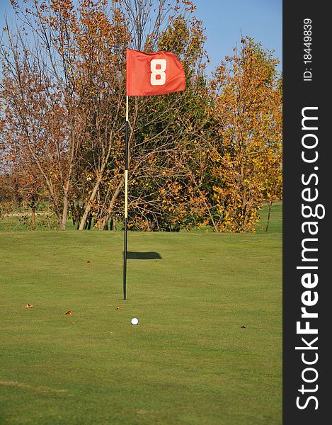 Golf field.flag and trees with autumn colors