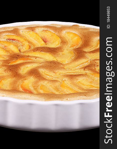 Peach tart in a white pottery cake tin. Isolated on black