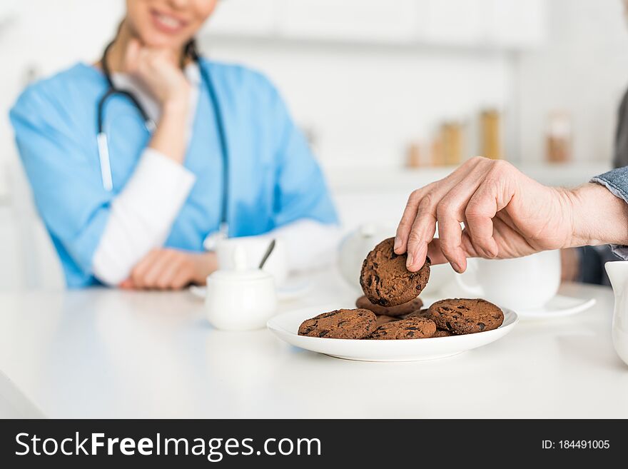 Selective focus of man hand with cookie and nurse on background