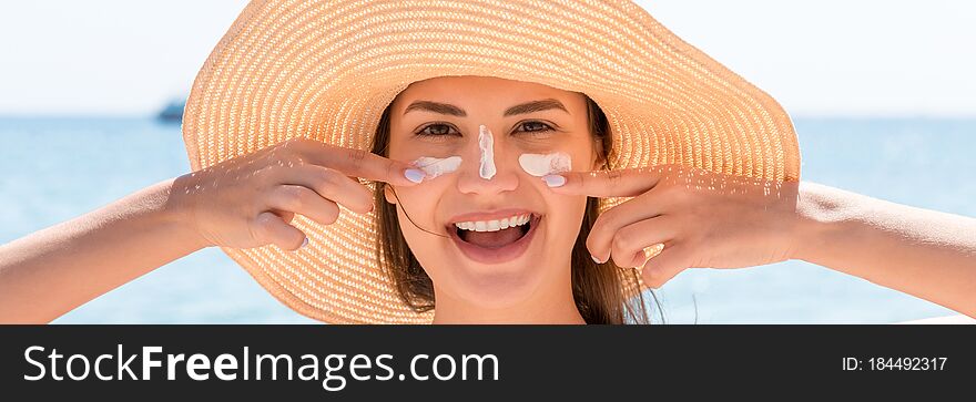 Beautiful Young Woman In Hat Is Applying Sunblock Under Her Eyes And On Her Nose Like Indian. Sun Protection Concept