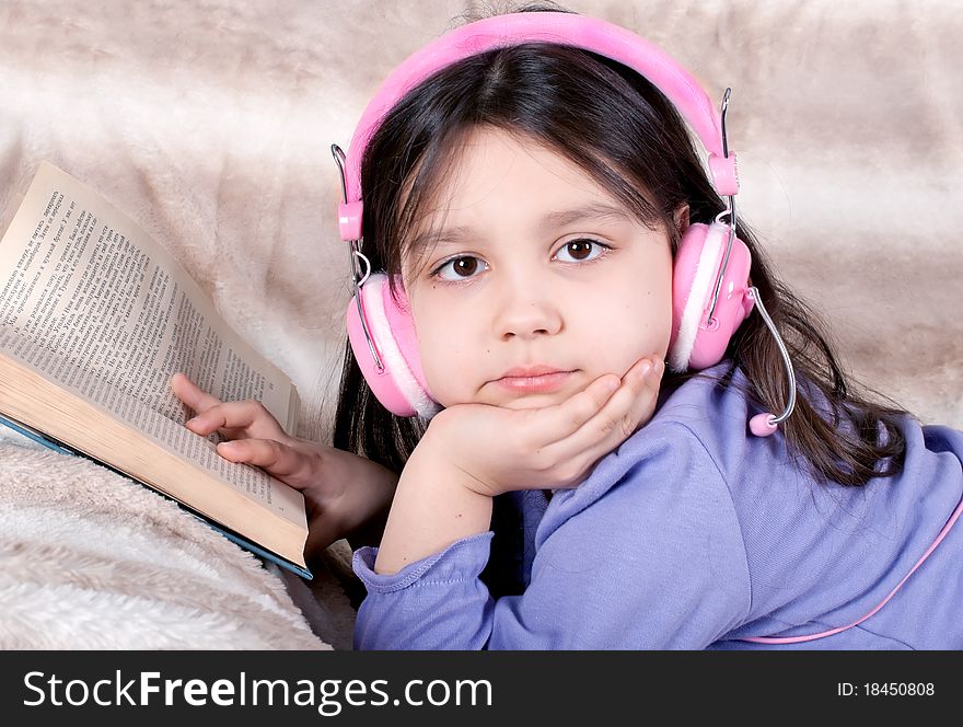 Little girl read a book and listen music