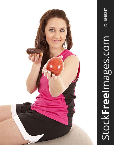 A woman in fitness attire is handing an apple and keeping the donut. A woman in fitness attire is handing an apple and keeping the donut.