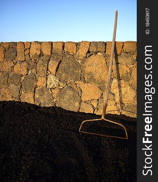 Garden agricultural old rake tool with lava and warm brick wall. Garden agricultural old rake tool with lava and warm brick wall.