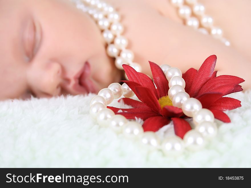 Beautiful baby girl sleeping, pearls draped with flower. FOCUS ON FLOWER AND PEARLS. Beautiful baby girl sleeping, pearls draped with flower. FOCUS ON FLOWER AND PEARLS.