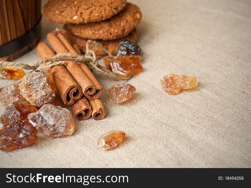 Still life of brown sugar, cinnamon sticks and oat cookies on linen background. Still life of brown sugar, cinnamon sticks and oat cookies on linen background