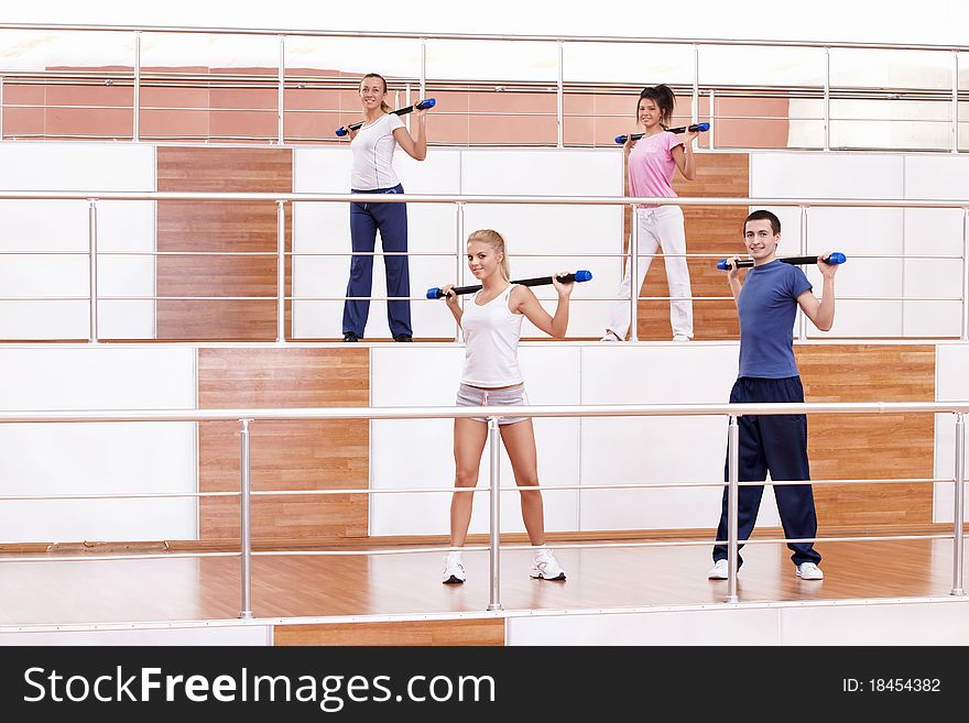 Attractive young people doing exercises in the fitness club. Attractive young people doing exercises in the fitness club