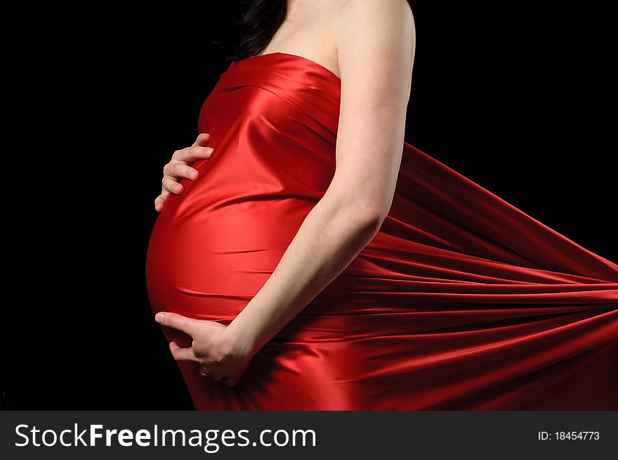 Pregnant young woman in red satin. Pregnant young woman in red satin