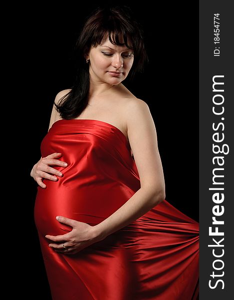 Pregnant young woman in red satin. Pregnant young woman in red satin