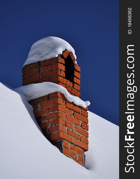 Russian winter: chimney and cottage roof all covered with snow against deep blue frozen sky. Russian winter: chimney and cottage roof all covered with snow against deep blue frozen sky