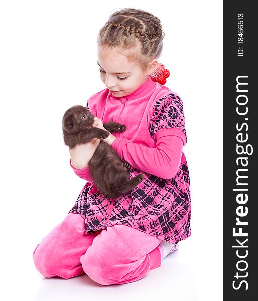 A smiling girl is playing with a kitten