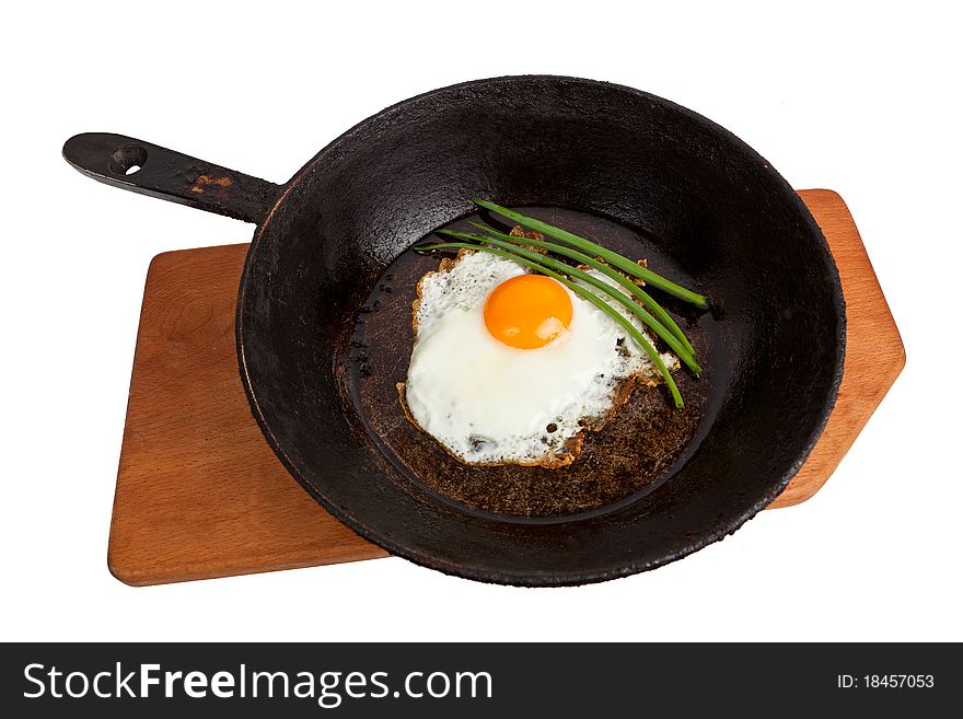 Fried eggs on a frying pan on a board on the isolated white background