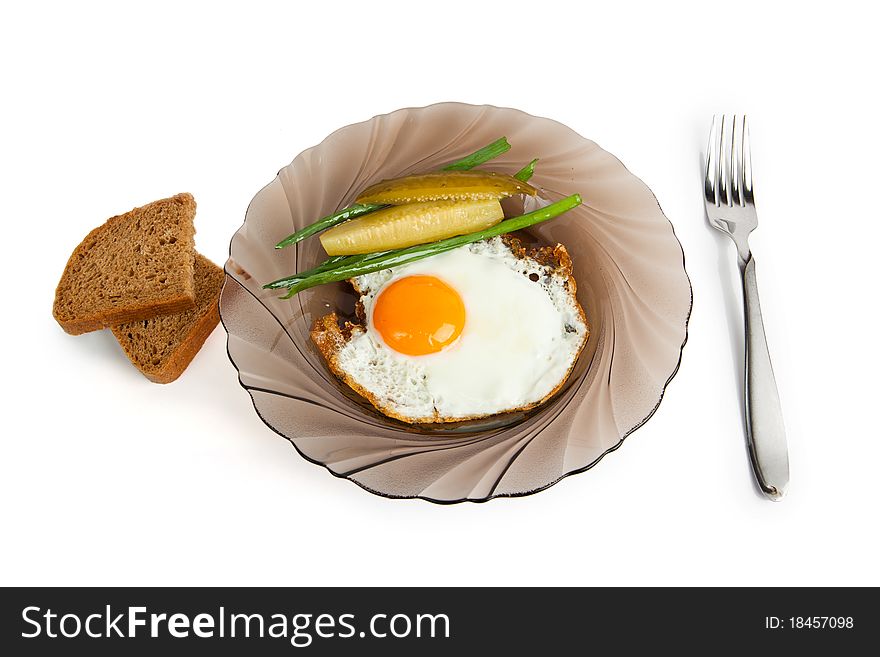 Breakfast Fried eggs on a glass plate, with a marinaded cucumber, fresh onions and rye bread